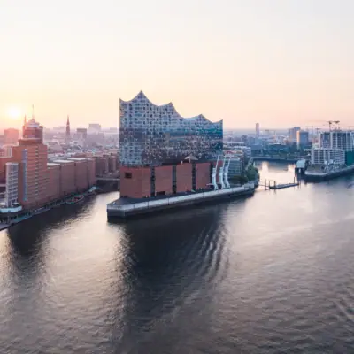 Philharmonie de l'Elbe Ville avec un fleuve et des bâtiments ; au premier plan, un bateau sur l'eau.