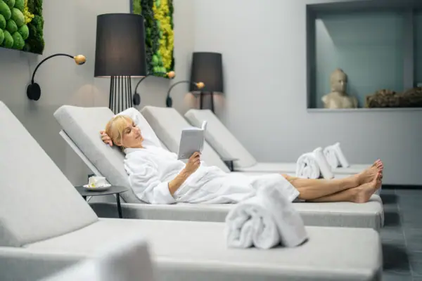 Wellnessbereich Louis C. Jacob Hamburg Eine Frau liegt auf einer Chaiselongue und liest ein Buch in einem Wellnessbereich.