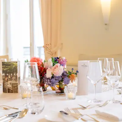 Veranstaltungsraum Ein Tisch mit Blumenarrangement und Gläsern.